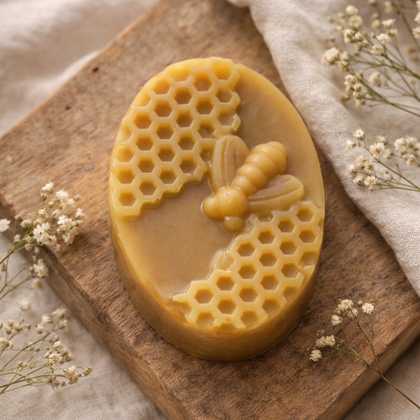 Beeswax bar with honeycomb and bee design on a wooden board with flowers.