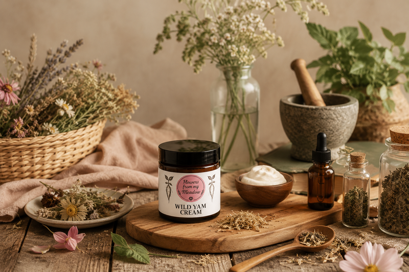 Flowers from my Meadow Wild Yam Cream on a wooden tray surrounded by botanicals