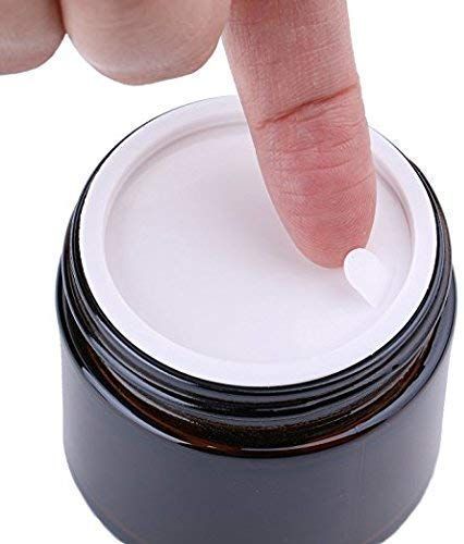 Hand showing inner plastic shive of a amber glass jar on a white background