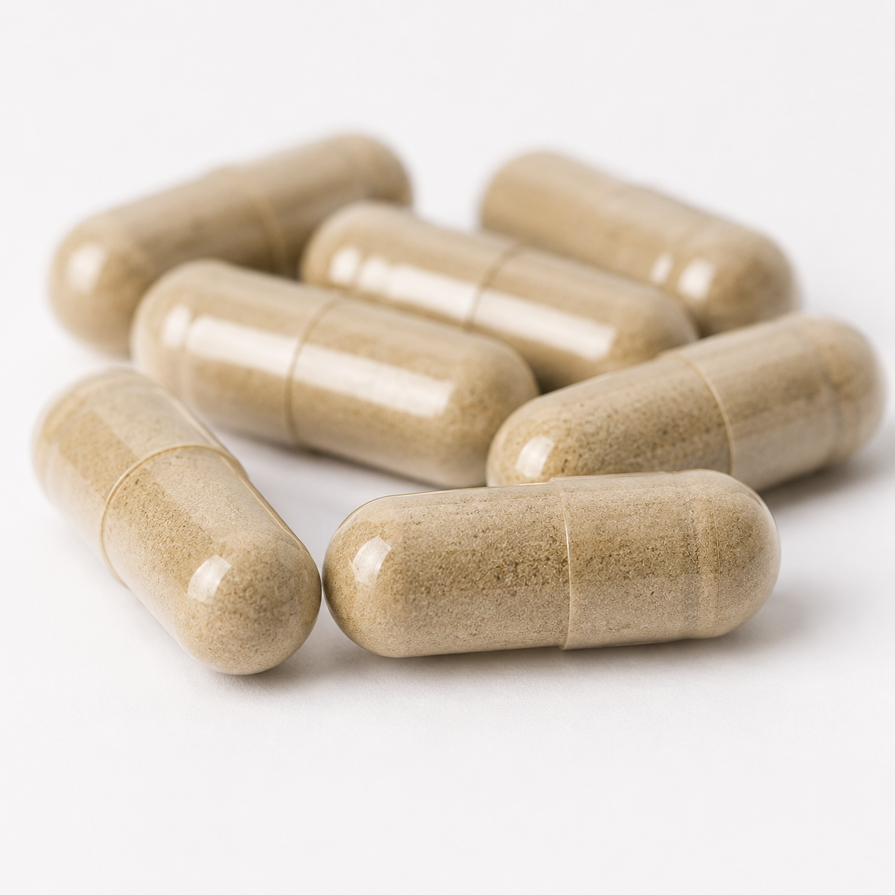 Several beige herbal supplement capsules arranged on a clean white background.