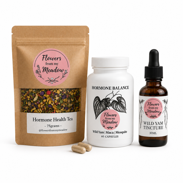 Three supplement products from Flowers from my Meadow on a white background: a brown stand-up pouch of Hormone Health Tea, a white bottle of Wild Yam Maca & mesquite capsules, and a dark amber dropper bottle of Wild Yam Tincture, with two capsules in front.