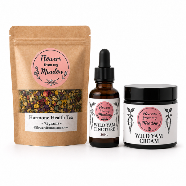 Three products from Flowers from my Meadow arranged on a white background: a kraft pouch of Hormone Health Tea, an amber dropper bottle of Wild Yam Tincture, and a black jar of Wild Yam Cream.