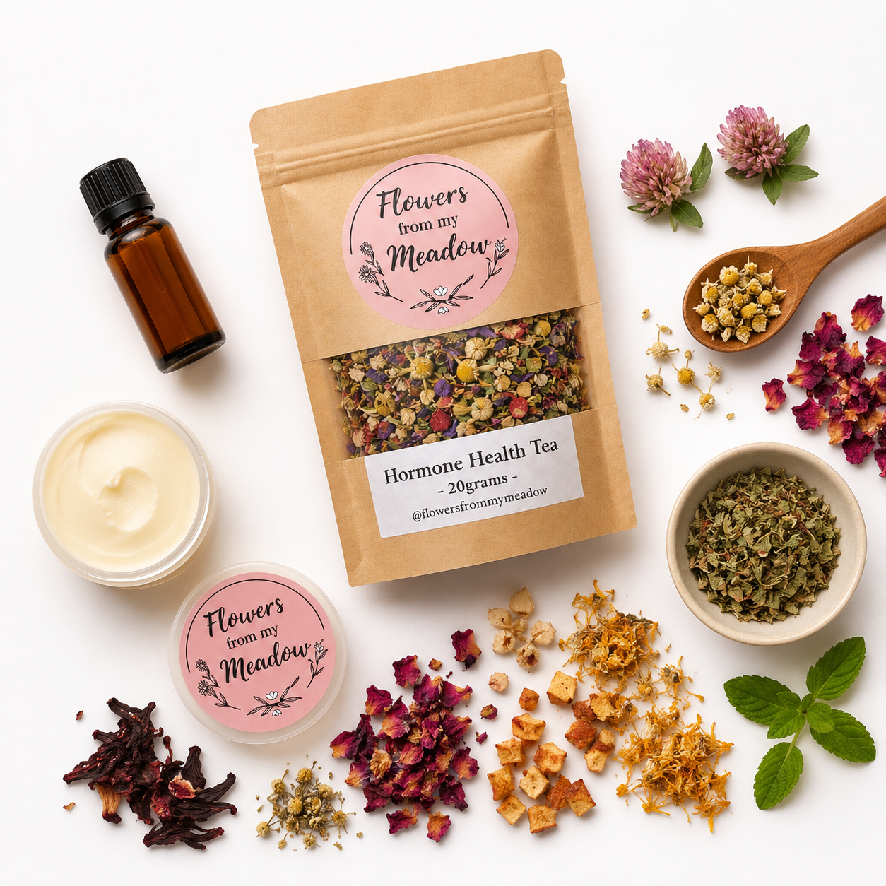 A styled flat-lay of a kraft paper stand-up pouch labeled 'Flowers from my Meadow' and 'Hormone Health Tea - 20grams', surrounded by loose dried flowers, a small amber bottle, a cream jar, and bowls of tea ingredients on a white background.