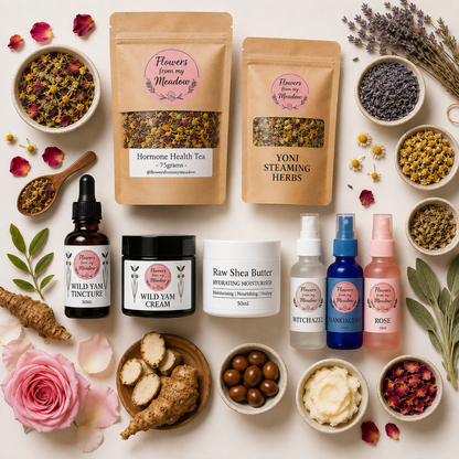 A beautifully arranged flat-lay of a herbal and skincare gift set on a light cream background. The set includes two kraft paper pouches of 'Flowers from my Meadow' (Hormone Health Tea and Yoni Steaming Herbs), three bottles (Wild Yam Tincture, Wild Yam Cream, Witch Hazel), a jar of Raw Shea Butter, and bowls of dried botanicals, rose petals, and fresh herbs.