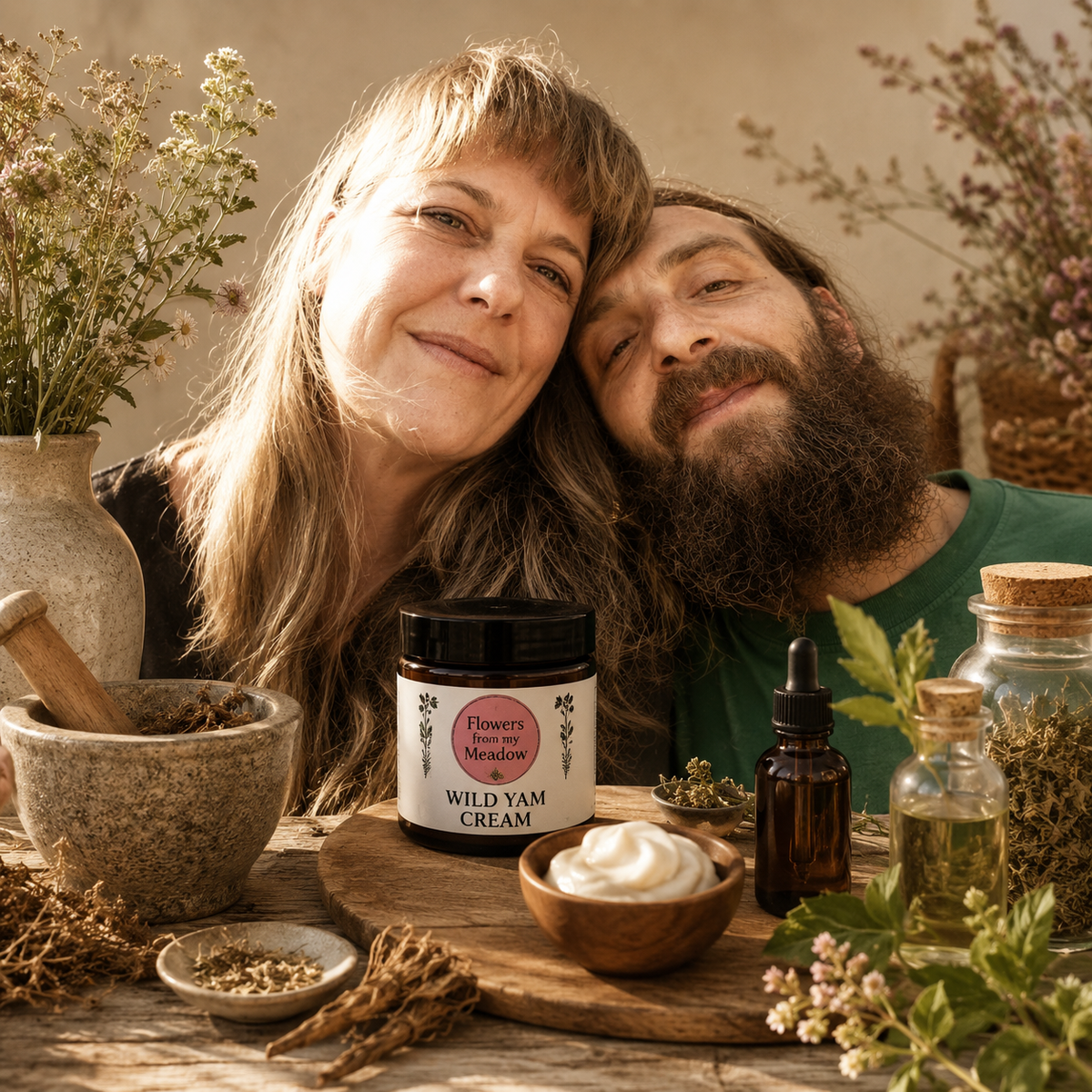 Two people leaning on a table with natural products including a jar of wild yam cream and bottles.