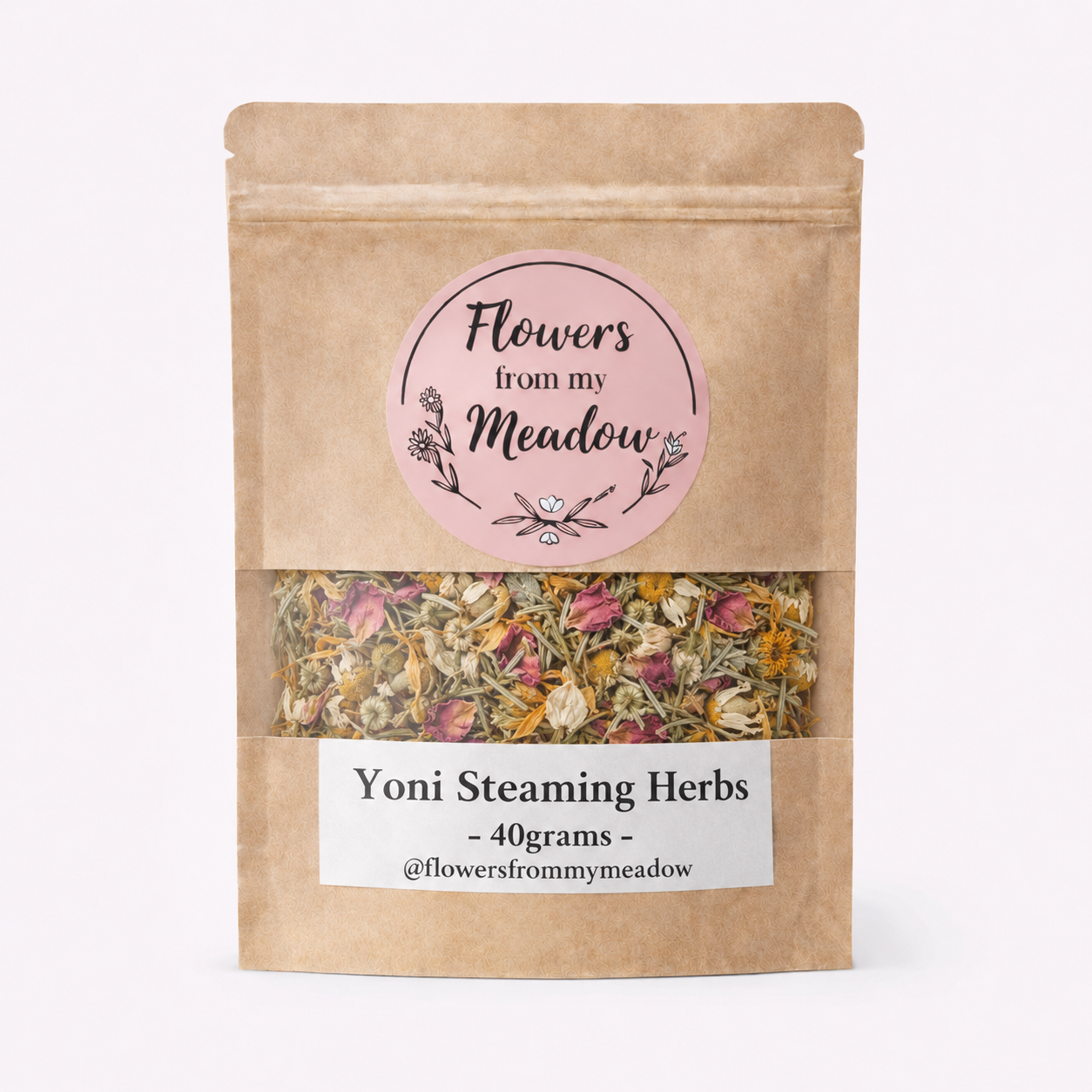 A kraft paper stand-up pouch of 'Flowers from my Meadow' Yoni Steaming Herbs, showing a clear window with dried herbs inside, on a clean white background.