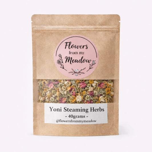 A kraft paper stand-up pouch of 'Flowers from my Meadow' Yoni Steaming Herbs, showing a clear window with dried herbs inside, on a clean white background.