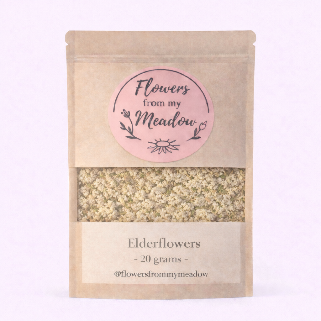 Kraft paper packaging with a pink label for 'Flowers from my Meadow' elderflowers on a light purple background.